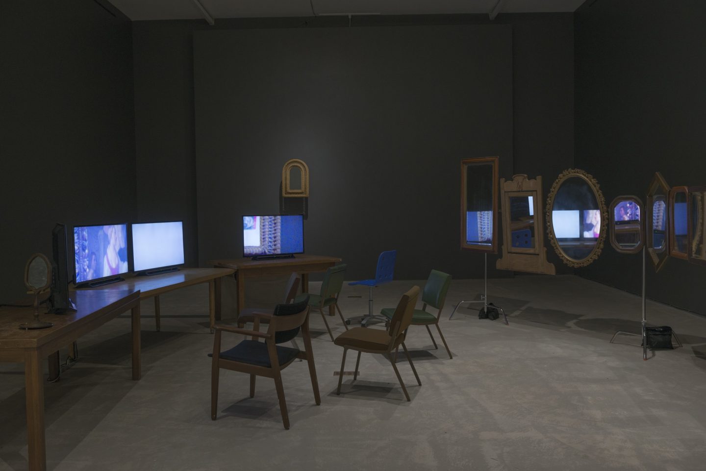 A room filled with chairs and tables, and the tables have computer monitors on them