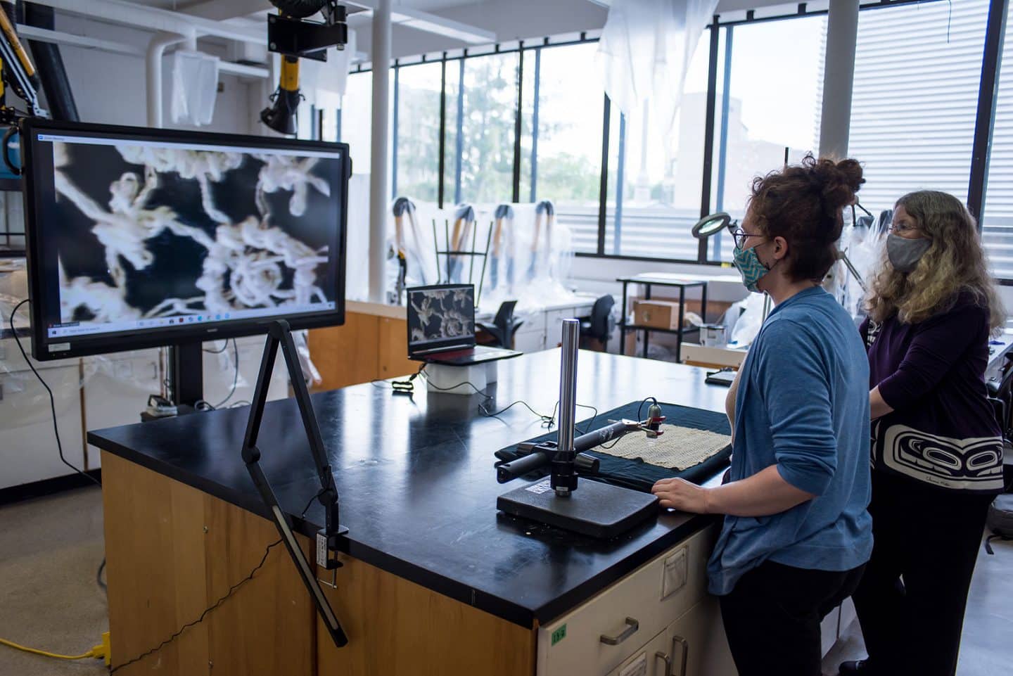 Working in the object conservation lab in Art Conservation's labs , Laura Peers and Anne-Marie Guérin demonstrate the multiple-camera setup used to provide visits with Indigenous ancestors in Agnes’s care.