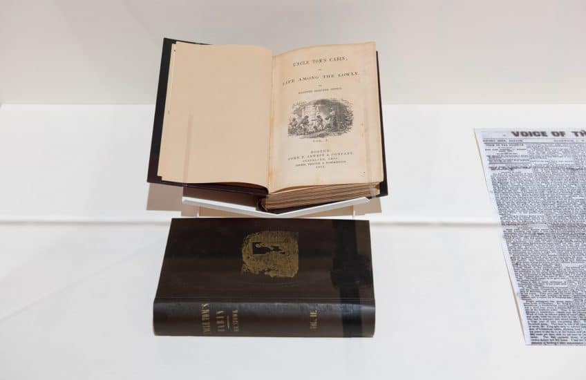A view of two copies of Harriet Beecher Stowe's Uncle Tom’s Cabin; or Life Among the Lowly from 1852. One is displayed open to the frontispiece and the other closed.