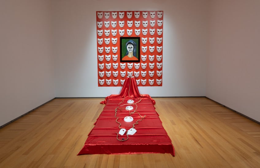 Winsom Winsom, The Masks We Wear, 2018, papier maché masks, slave ring, self-portrait (oil on canvas), painted seeds, red paint, wooden snakes, red satin. Purchase, Chancellor Richardson Memorial Fund, 2022