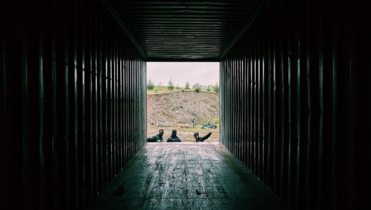 View from inside a storage container looking out at Chaka Chikodzi and two assistants opening the doors.