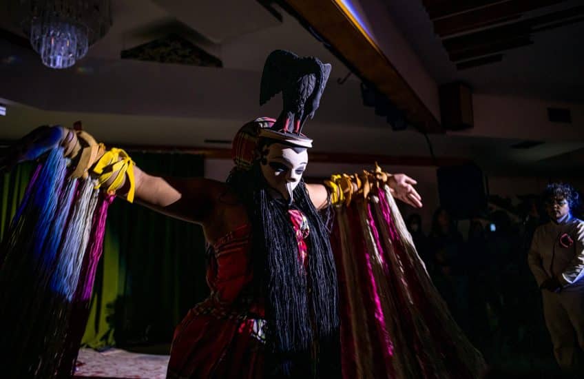 A dancer wearing a bird mask from Ogoniland performs at the Illicit Gin Institute.