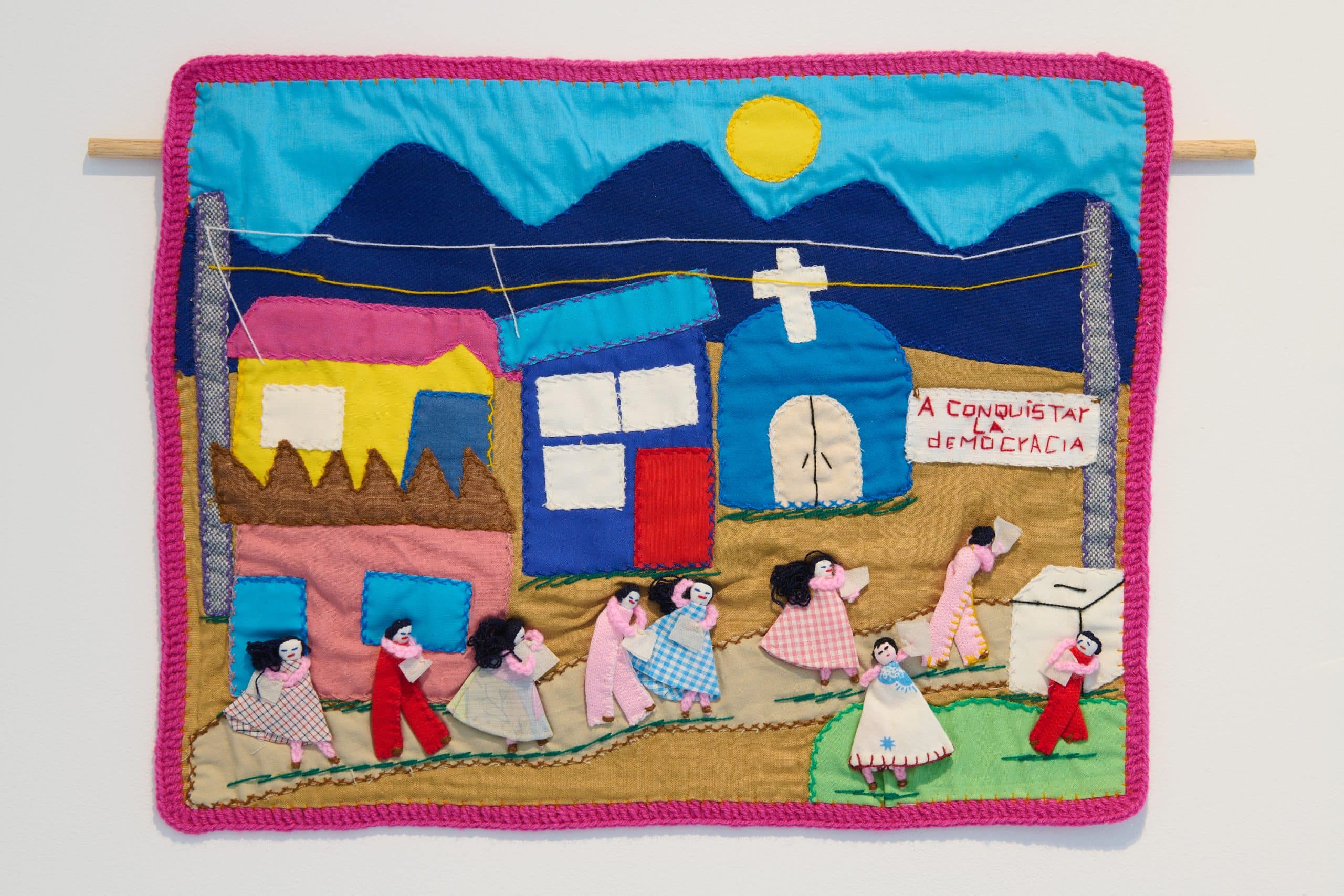 An arpillera depicting a mountainous town where people line up to cast their ballots.