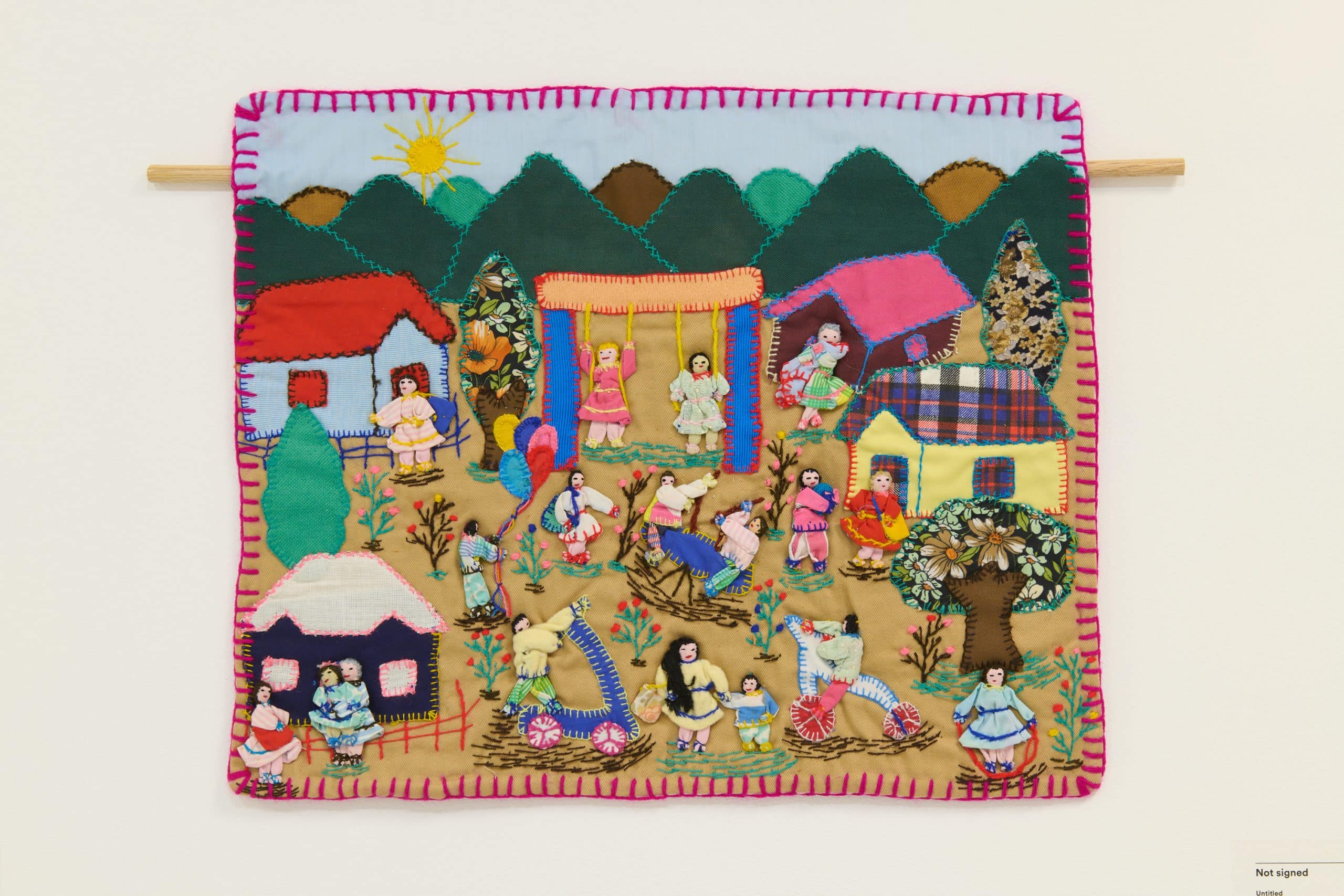 An arpillera depicting a colourful community scene with growing plants and children playing.
