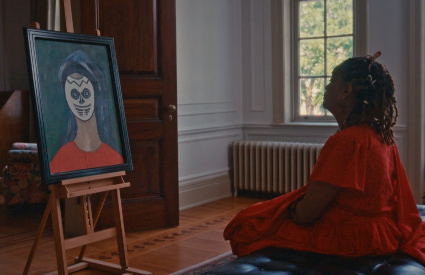 In a historical house, Winsom Winsom sits and contemplates her painting.