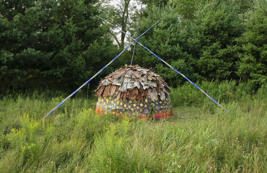 Bark and cloth lodge set up in a field