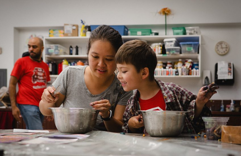 A parent and child enthusiastically working on a craft during a Creation Station