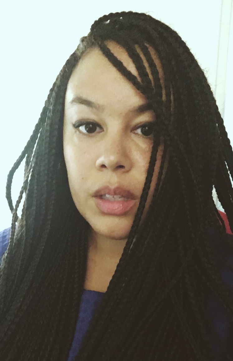 Young woman of colour with long dark braids that fill much of the image frame