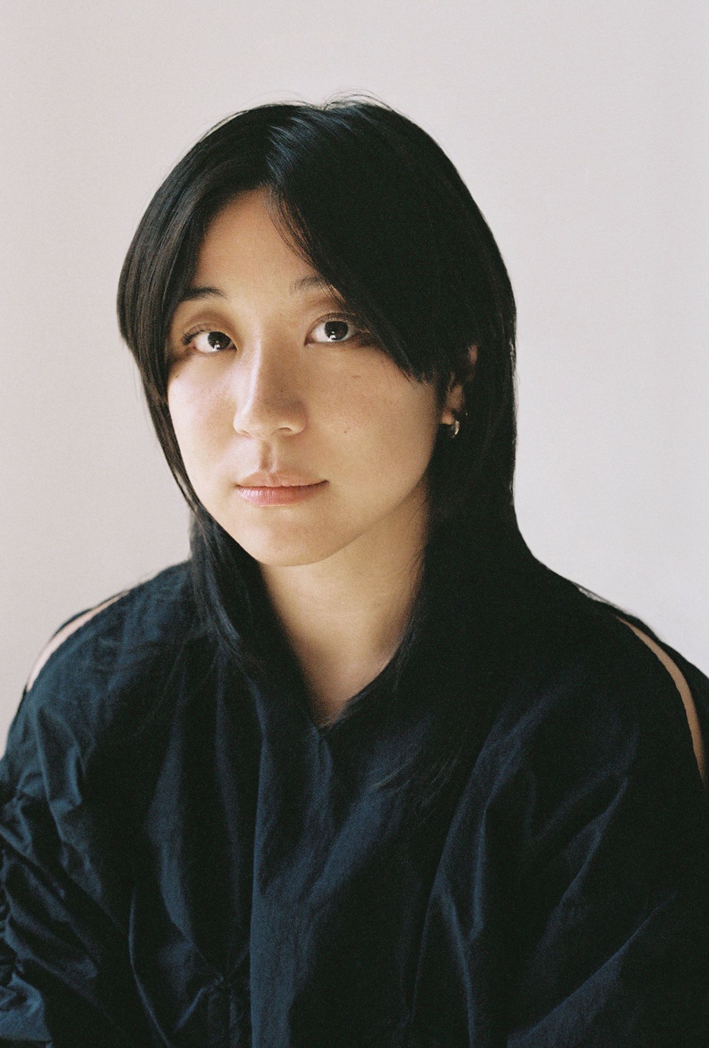 Woman with long dark hair in a dark shirt looking intensely at the camera