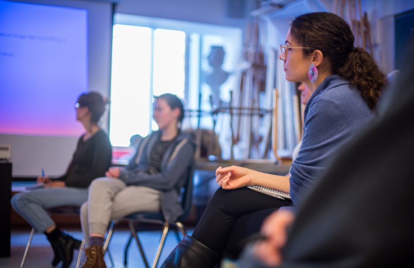 people sitting in a circle in a room listening intently.