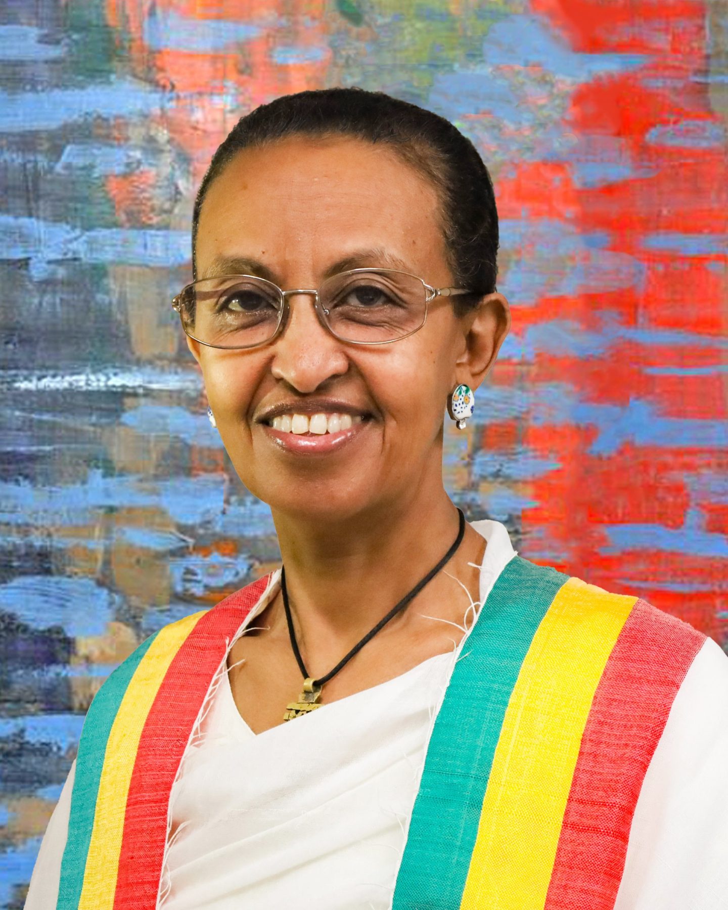 Woman wearing a tricolour scarf (green, yellow, red) and glasses looking at the camera