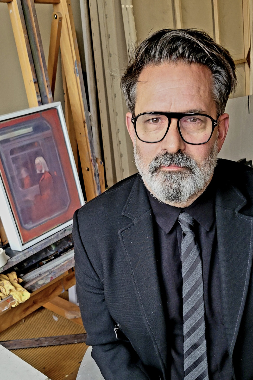 Man with beard and glasses and a suit looking directly into camera