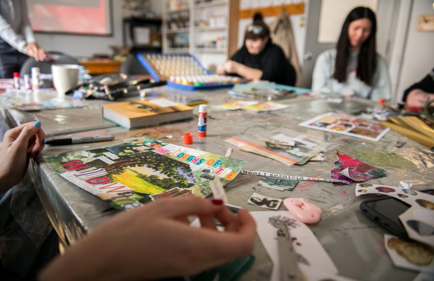 People sitting around a table participating in a collage craft.